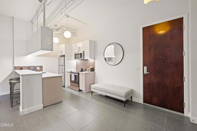 kitchen featuring sink, appliances with stainless steel finishes, a kitchen breakfast bar, white cabinets, and kitchen peninsula