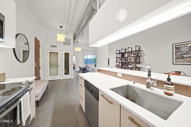 kitchen featuring dishwasher, sink, hanging light fixtures, dark tile patterned floors, and light brown cabinets