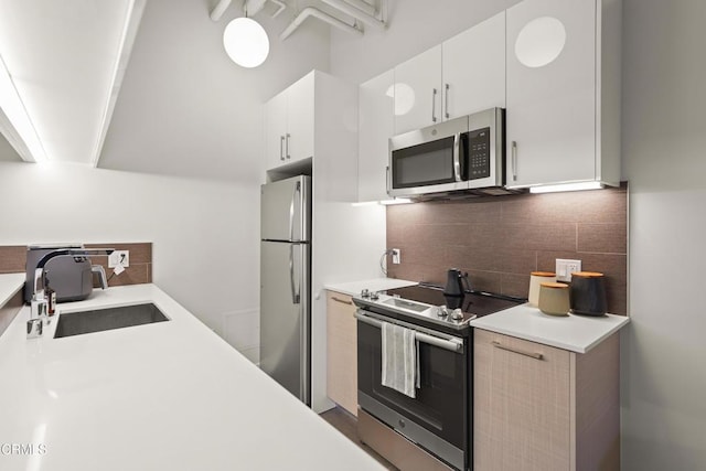 kitchen with stainless steel appliances, sink, white cabinets, and decorative backsplash