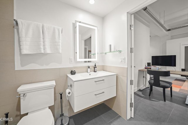 bathroom with tile patterned floors, toilet, tile walls, and vanity