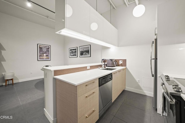 kitchen featuring stainless steel appliances, kitchen peninsula, dark tile patterned floors, and light brown cabinets