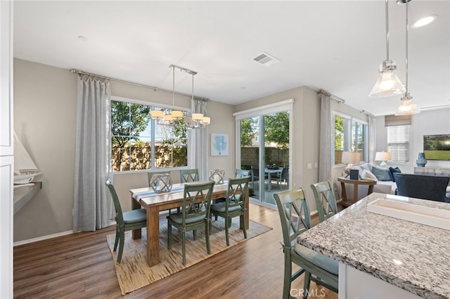 dining area with an inviting chandelier, baseboards, visible vents, and dark wood-type flooring