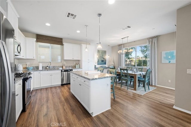 kitchen featuring white cabinetry, visible vents, appliances with stainless steel finishes, a center island, and pendant lighting