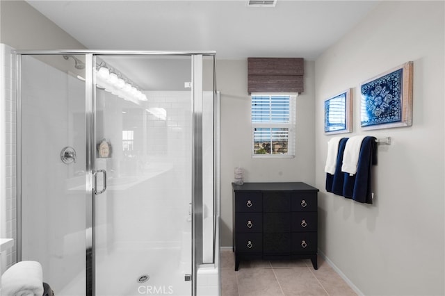 bathroom with a stall shower, tile patterned flooring, and baseboards