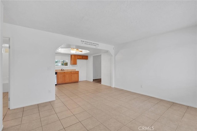 unfurnished living room featuring ceiling fan, sink, and light tile patterned floors