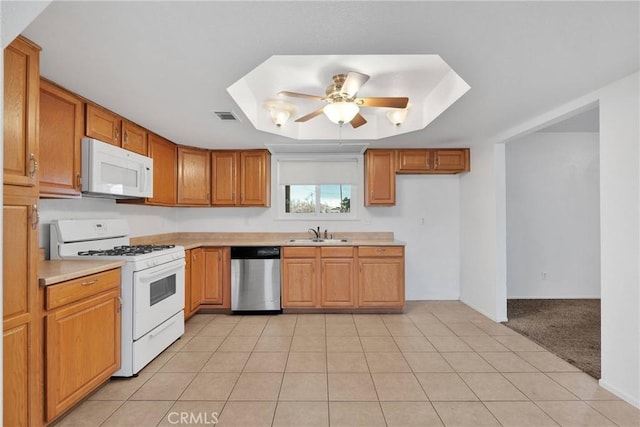 kitchen featuring sink, light tile patterned floors, ceiling fan, a tray ceiling, and white appliances