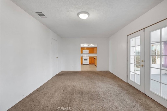 carpeted spare room featuring french doors and a textured ceiling