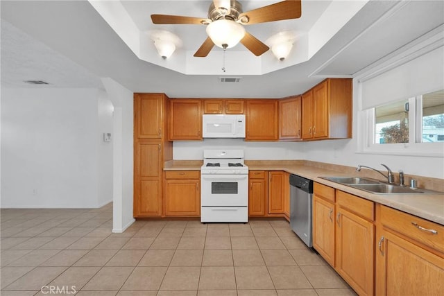 kitchen featuring sink, white appliances, light tile patterned floors, a tray ceiling, and ceiling fan