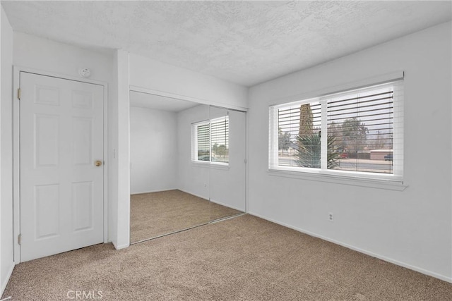 unfurnished bedroom with light carpet, a closet, and a textured ceiling