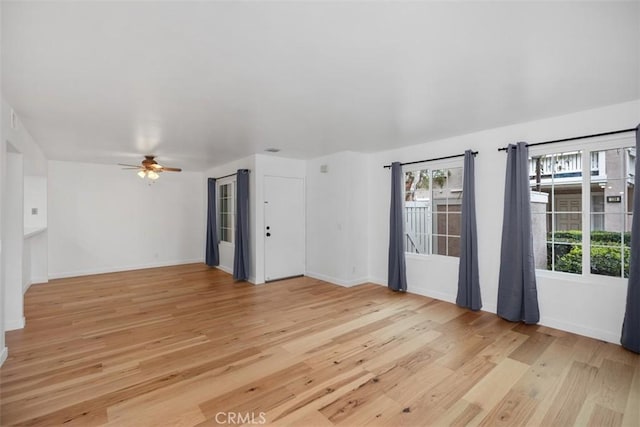 unfurnished room with baseboards, light wood-type flooring, and a healthy amount of sunlight