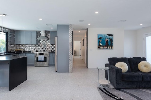 kitchen with stainless steel appliances, wall chimney range hood, and backsplash