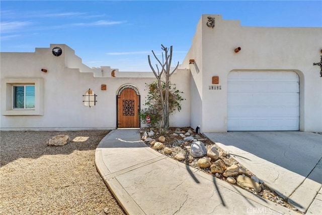 view of front of property featuring a garage, concrete driveway, and stucco siding