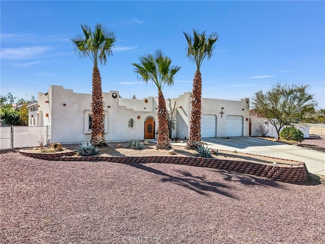 adobe home with a garage, concrete driveway, fence, and stucco siding