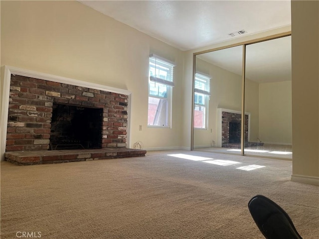 unfurnished living room featuring a high ceiling, a brick fireplace, and carpet floors