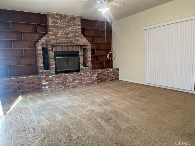 unfurnished living room with ceiling fan, built in features, a brick fireplace, and carpet