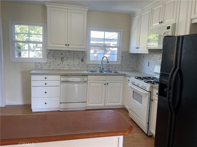 kitchen with white cabinetry, sink, white appliances, and a wealth of natural light