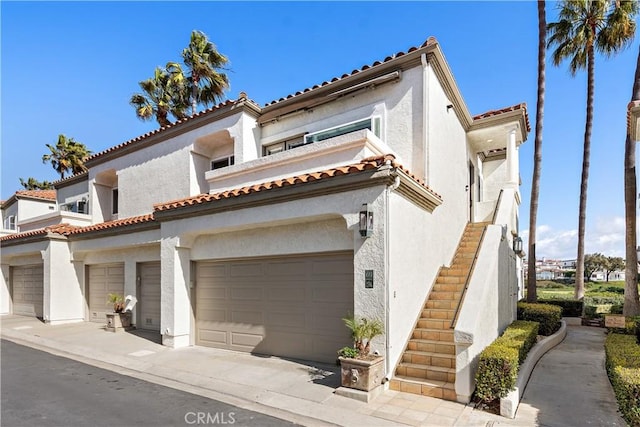 mediterranean / spanish home with stairs, an attached garage, and stucco siding