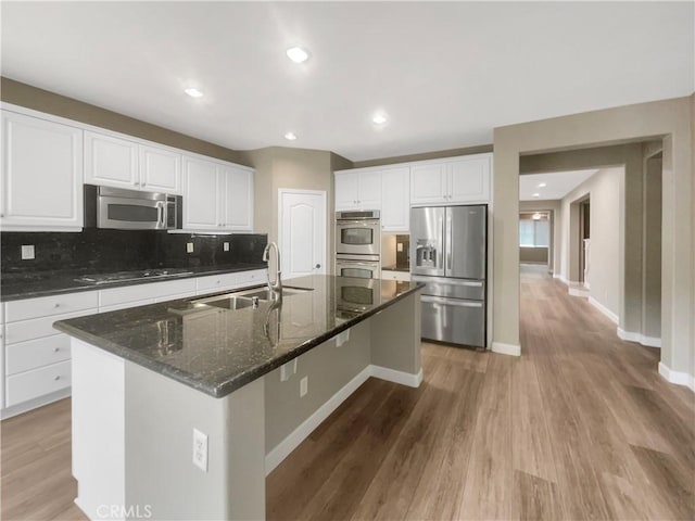 kitchen with stainless steel appliances, sink, a center island with sink, and white cabinets