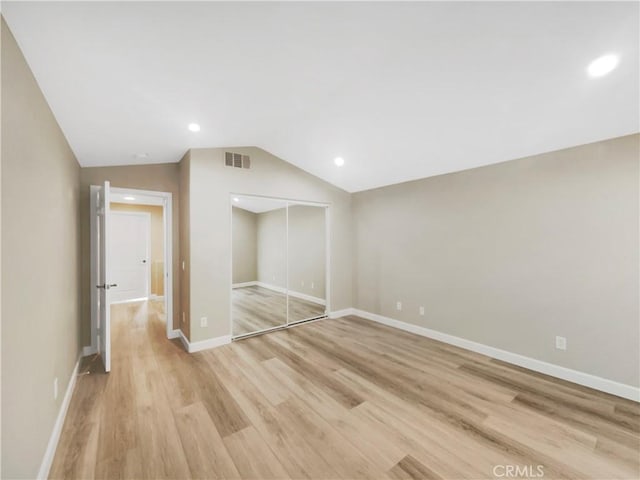 unfurnished bedroom with light hardwood / wood-style floors, vaulted ceiling, and a closet