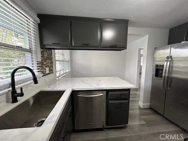 kitchen with appliances with stainless steel finishes, sink, a textured ceiling, and dark hardwood / wood-style flooring