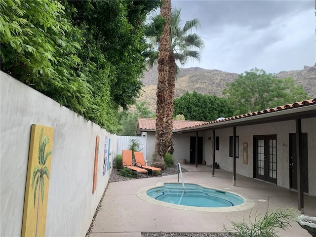 view of pool featuring french doors, a mountain view, a jacuzzi, and a patio area