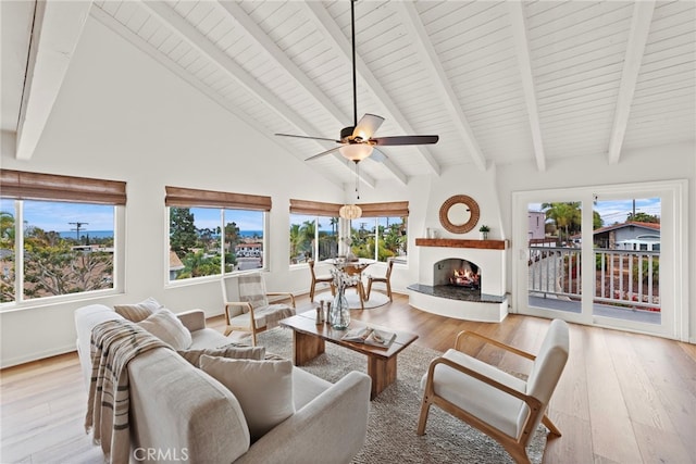 living room featuring high vaulted ceiling, a fireplace, ceiling fan, light hardwood / wood-style floors, and beam ceiling