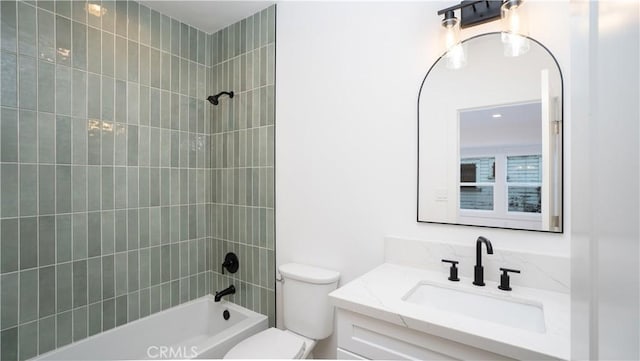 full bathroom featuring tiled shower / bath, vanity, and toilet