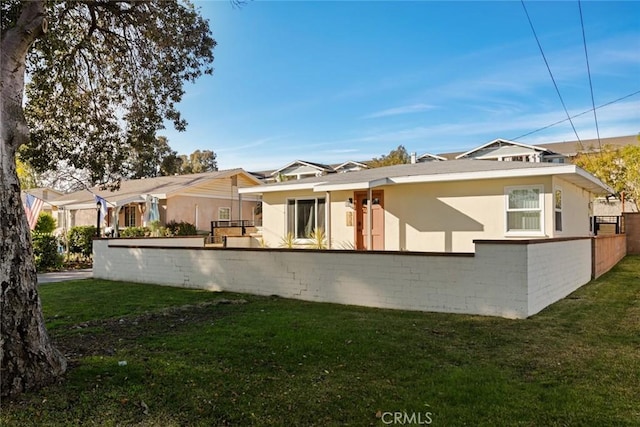 back of property featuring a yard, fence, and stucco siding