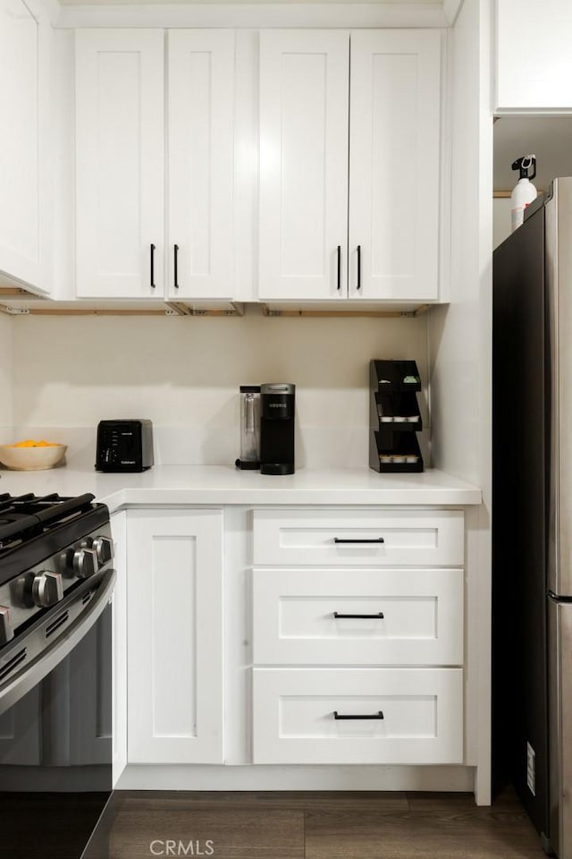 kitchen featuring white cabinetry, light countertops, range with gas stovetop, and freestanding refrigerator