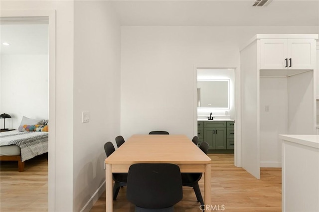 dining area featuring light wood-type flooring, visible vents, and baseboards