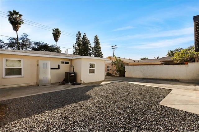 back of property with a patio area, central AC, fence, and stucco siding