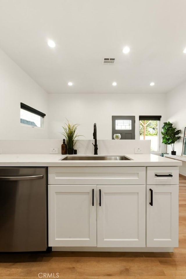 kitchen with visible vents, white cabinets, dishwasher, light countertops, and a sink