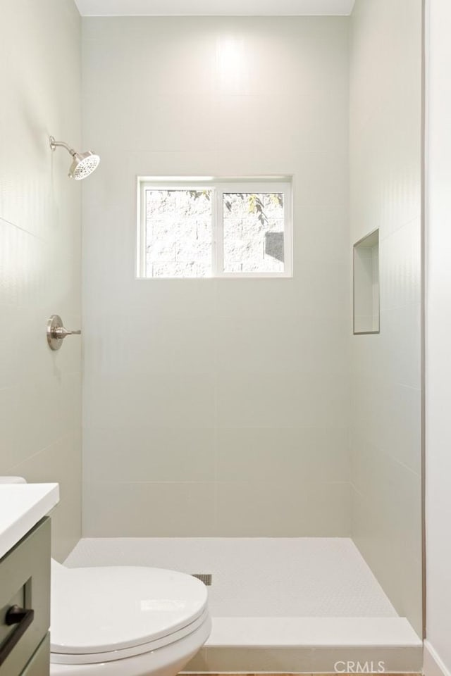 full bath with toilet, a tile shower, and vanity