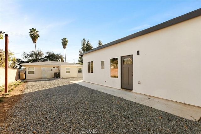 rear view of house featuring central air condition unit, fence, a patio, and stucco siding