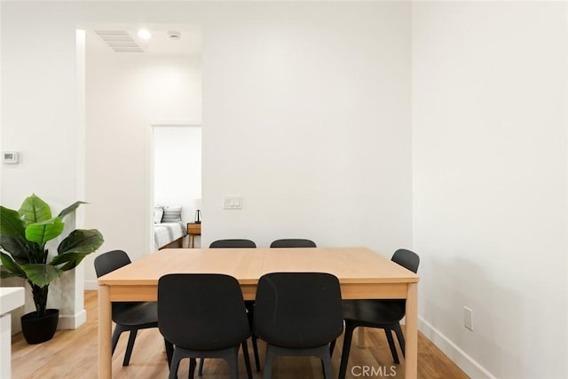 dining room featuring light wood-type flooring, visible vents, and baseboards