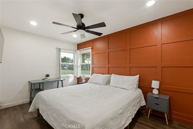 bedroom with a decorative wall, dark wood-style flooring, and recessed lighting