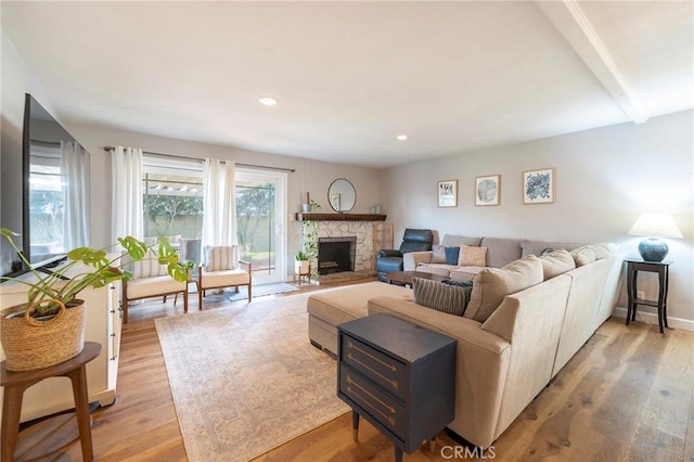 living room with beam ceiling, a fireplace, and light wood-type flooring