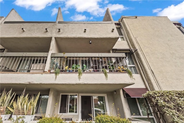 back of property featuring a balcony and stucco siding