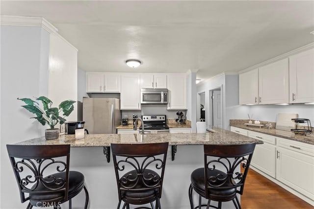 kitchen with white cabinetry, appliances with stainless steel finishes, and light stone counters