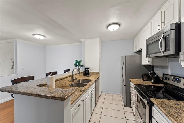 kitchen featuring appliances with stainless steel finishes, dark stone countertops, sink, and white cabinets