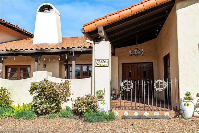 entrance to property with a chimney and stucco siding