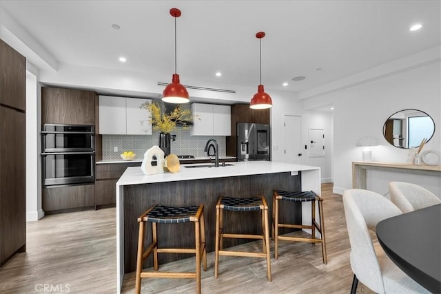 1304 N Mansfield Ave, Los Angeles, CA 90028 - kitchen featuring appliances with stainless steel finishes, modern cabinets, a breakfast bar, white cabinets, and recessed lighting