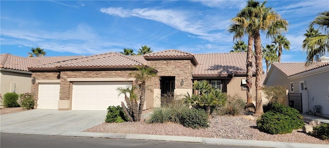 mediterranean / spanish house featuring an attached garage, stone siding, concrete driveway, a tiled roof, and stucco siding