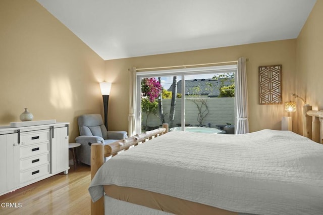 bedroom featuring access to exterior, light hardwood / wood-style floors, and vaulted ceiling