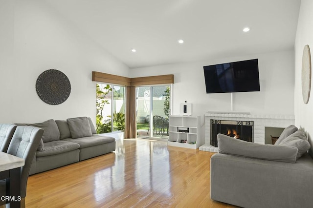 living room featuring lofted ceiling, a fireplace, and wood-type flooring