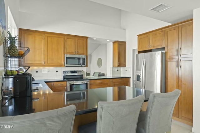 kitchen featuring stainless steel appliances, vaulted ceiling, decorative backsplash, and kitchen peninsula