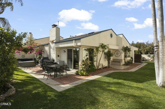 rear view of house featuring a jacuzzi, a patio area, and a lawn