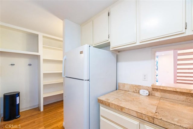 kitchen with white refrigerator, white cabinetry, and light hardwood / wood-style floors