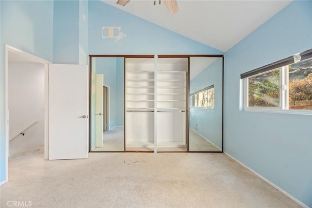 unfurnished bedroom featuring ceiling fan, high vaulted ceiling, light carpet, and two closets