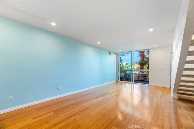 empty room featuring a wall of windows and light hardwood / wood-style floors